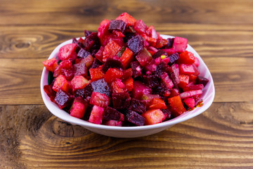 Traditional russian salad vinaigrette with beetroot, carrot, potato, onion and pickled cucumbers on wooden table