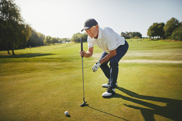 Senior golfer planning his putt on a golf green