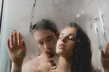 selective focus of hot naked man and attractive woman hugging in shower cabin