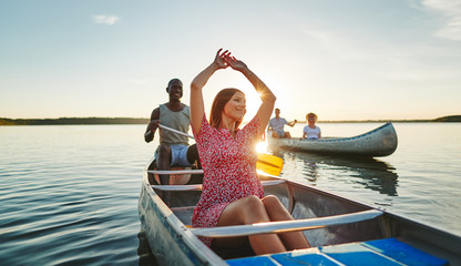 Carefree young woman enjoying the freedom of canoeing with frien