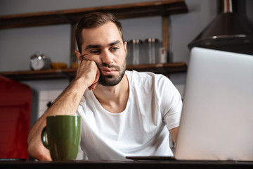 Bored young man using laptop computer