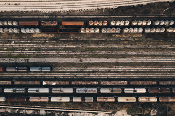 Aerial view old railroad tracks with rusty abandoned trains and freight cars at dusk day in the evening. Old depot of the big city. Railroad texture. Top view. Heavy industry. Industrial conceptual