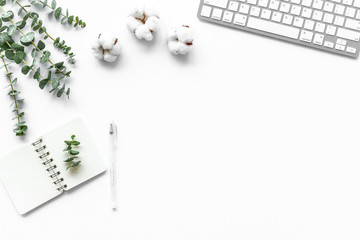 Laptop, cotton branch on white table. Flat lay, top view minimal freelancer home office desk workspace.