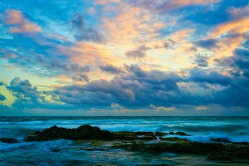 Dramatic sunrise low hanging clouds over wavy blue ocean at San Juan, Peurto Rico
