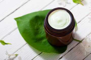 cosmetic creams and white lilac blossom on bright wooden table background