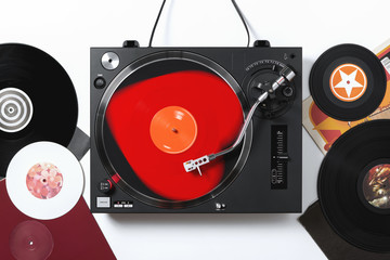  Top view of a turntable with red heart-shaped vinyl record a stylus with a needle, on white...