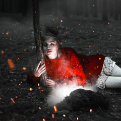A beautiful girl in a red sweater hugs a tree in a dark magical forest to the sounds of flying fireflies