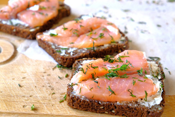 sandwiches with salmon sprinkled with herbs on a cutting board