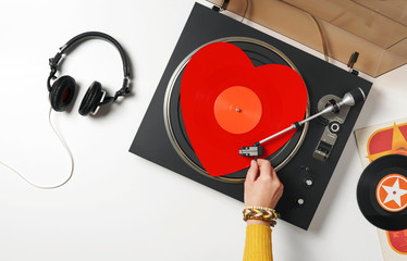 A red heart vinyl record turntable on a white table with plates. Included gramophone, black...