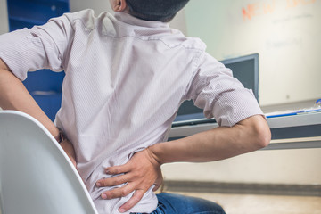 Young business employee feeling backache at the office