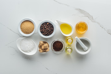 top view of different ingredients for homemade cosmetics, and pounder on white surface