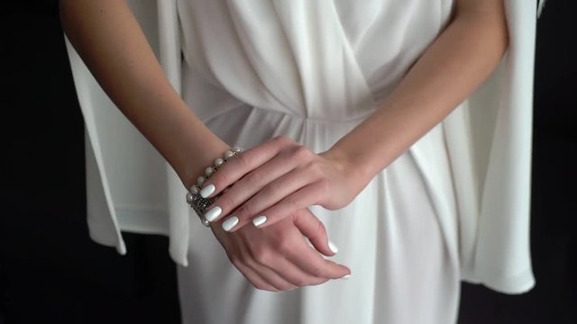 Bride in white wedding dress put on bracelet on her hand