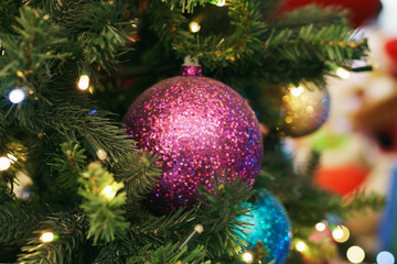 Christmas card. Christmas picture. Bright sparkling orange ball on fluffy branches of a Christmas tree. Background bokeh lights of garland. Ready Christmas background for your text. Glitter.