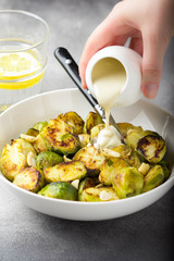 Roasted Brussels sprouts with peanuts and white sauce, delicious vegetarian lunch. Healthy, organic food, vegetable garnish