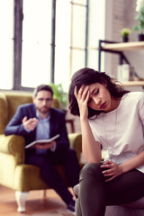 Cheerless upset young woman visiting a psychologist