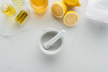 top view of lemons, pounder and various natural ingredients for cosmetics making on white surface