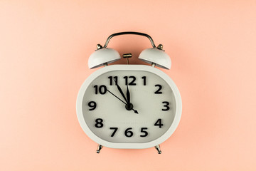 white vintage alarm clock on pink background. - top view.