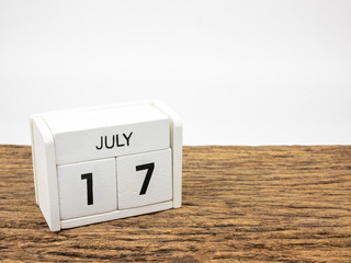 July 17 white cube wooden calendar on vintage wood and white background with summer day, Copyspace for text