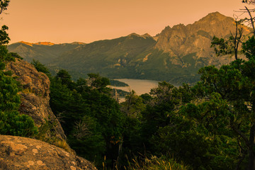 atardecer sobre un lago rodeado de montañas y bosques
