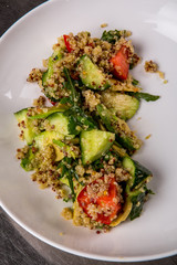 quinoa salad with tomato, cucumber, lemon and avocado on a white plate