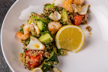 quinoa salad with tomato, cucumber, lemon and avocado on a white plate