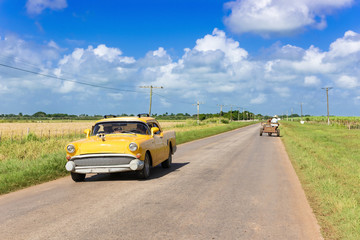 Amerikanischer gelber Oldtimer unterwegs auf der Landstrasse nach Havanna in Cuba - Serie Kuba Reportage