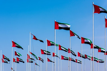 United Arab Emirates flags winding in the wind against blue sky