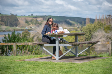 Woman with daughter relaxing for a picnic on a park bench table