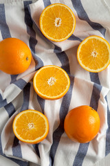 Halved and whole oranges on cloth, top view. Overhead, from above, flat lay. Close-up.
