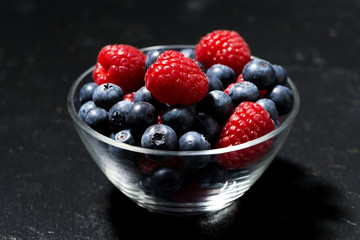 fresh berries in a glass bowl on dark background