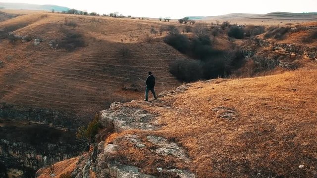 man pees on the edge of a cliff high in the mountains