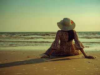 Women wearing vintage dresses are sitting on the beach with excitement to relax. Summer beach trips...