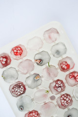 Obraz na płótnie Canvas Ice cubes with berries. Ice tray with berries on white background. Top view 