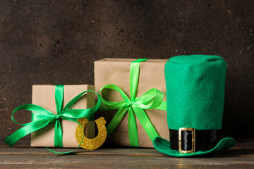St.Patrick 's Day. celebration. Green leprechaun hat and horseshoe and gift boxes on brown...