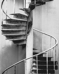 Rustic curved spiral staircase with railing close-up in black and white