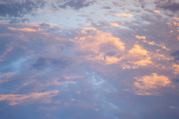 Naklejka na ściany i meble Evening clouds on a darkening sky, background, the light of the setting sun.