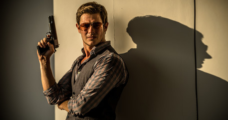 Fototapeta Young Caucasian male holding a gun in a sunset hotel obraz