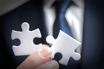 Business solutions and strategy concept of business man holding connecting pieces of puzzle