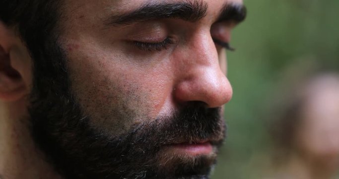 Man meditating outside in nature. Close-up of person face breathing in meditation