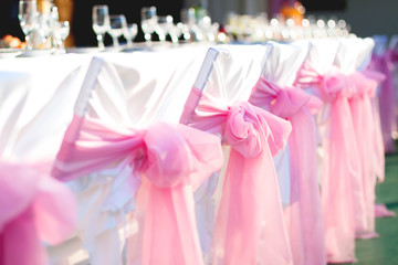 Wedding Banquet. White chairs with pink ribbons