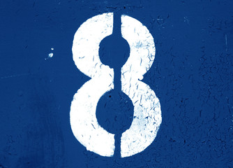 Number 8 in stencil on metal wall in navy blue tone.
