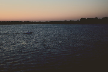 The boat floats on the river in the late evening