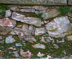 The old wall is made of stone blocks. Green moss grows on the surface of the old wall.
