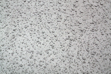 Water drops on grey car surface.