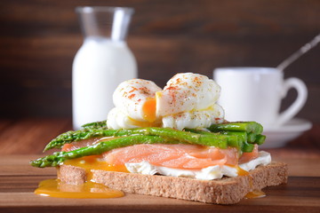 Poached egg with fried asparagus, cream cheese, salmon and spices on a toast. Poached egg with leak.Healthy French breakfast concept