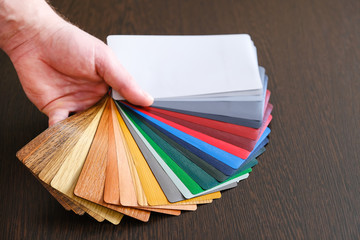 Samples of lamination deployed, the master holds in his hand. On a wooden background for lamination...
