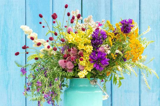 Bright colorful bouquet of wild flowers in starm tin can vase on background blue wooden boards. Template for postcard or your design Concept Women's day or Mothers Day, Hello summer Hello spring