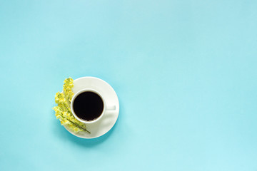 Cup of coffee and yellow wild flowers Linaria, blue paper background Flat lay Top view Concept Good...