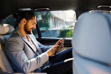 Businessman using digital tablet in a taxi