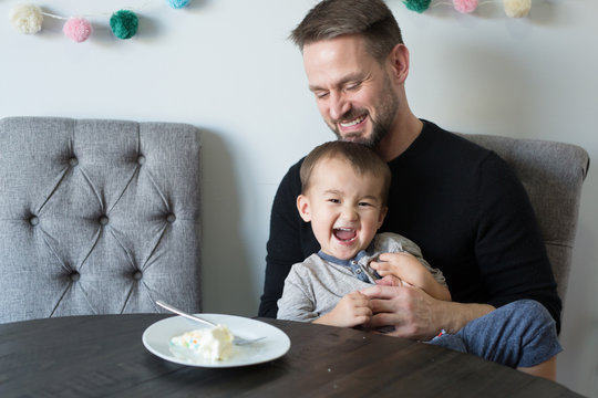 Smiling father and son having cake while sitting at home